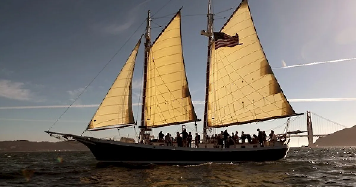 Executive team aboard a schooner on San Francisco Bay during a sailing offsite, the Golden Gate Bridge behind