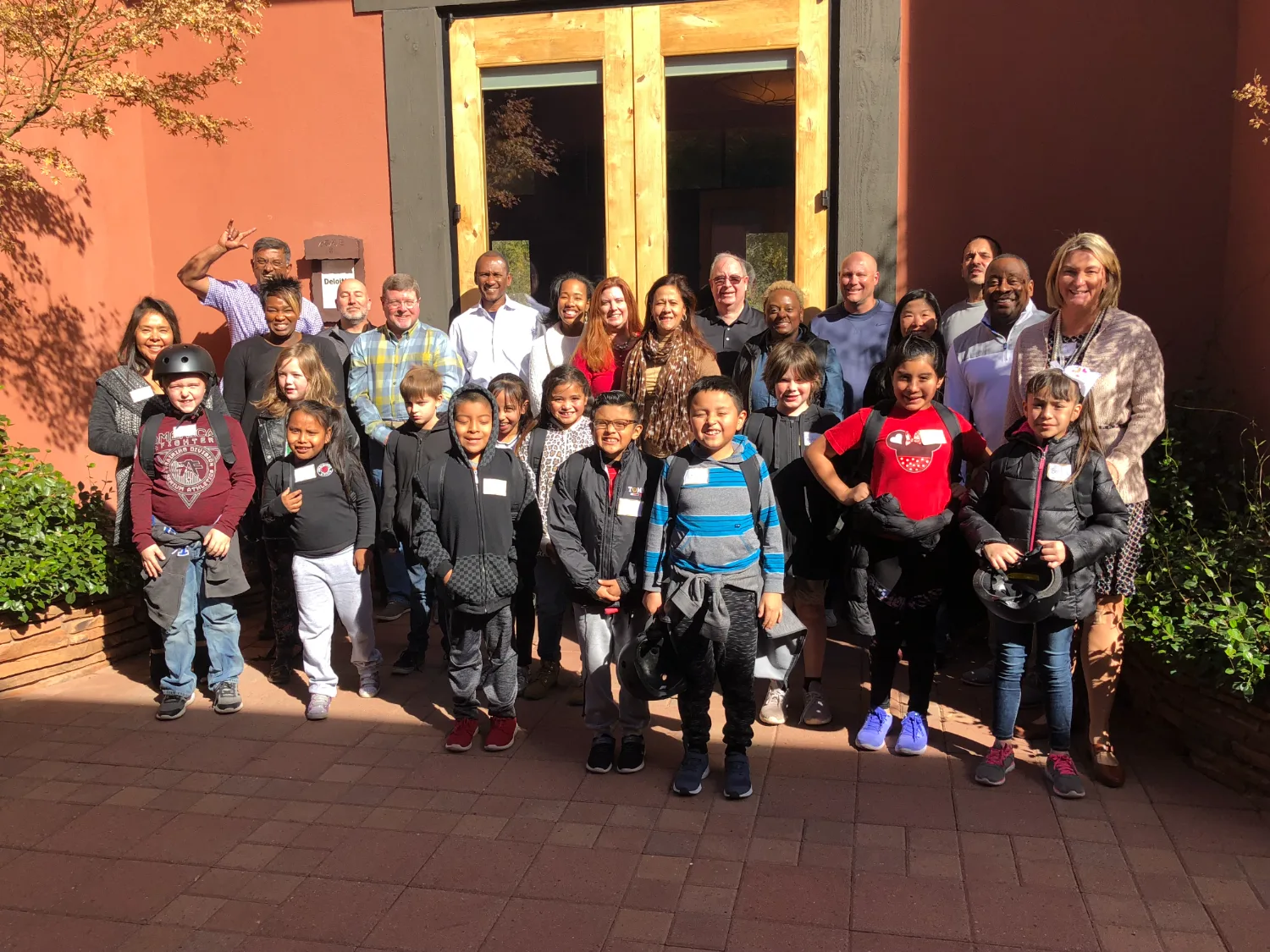 Executives and local kids together at a Be Legendary retreat lodge — the 1:1 social enterprise in action
