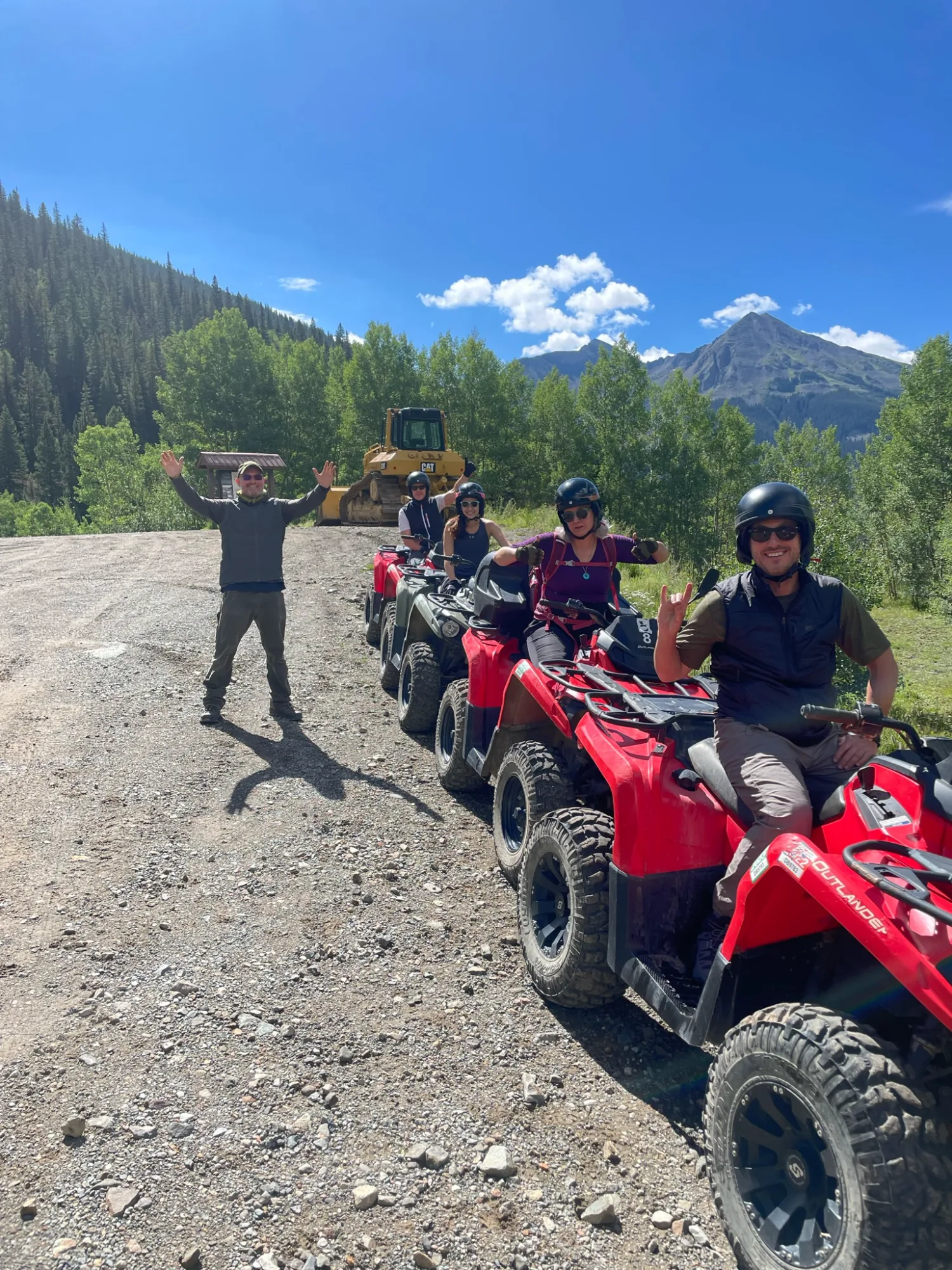An executive throwing his arms up with joy beside ATVs in the Colorado mountains