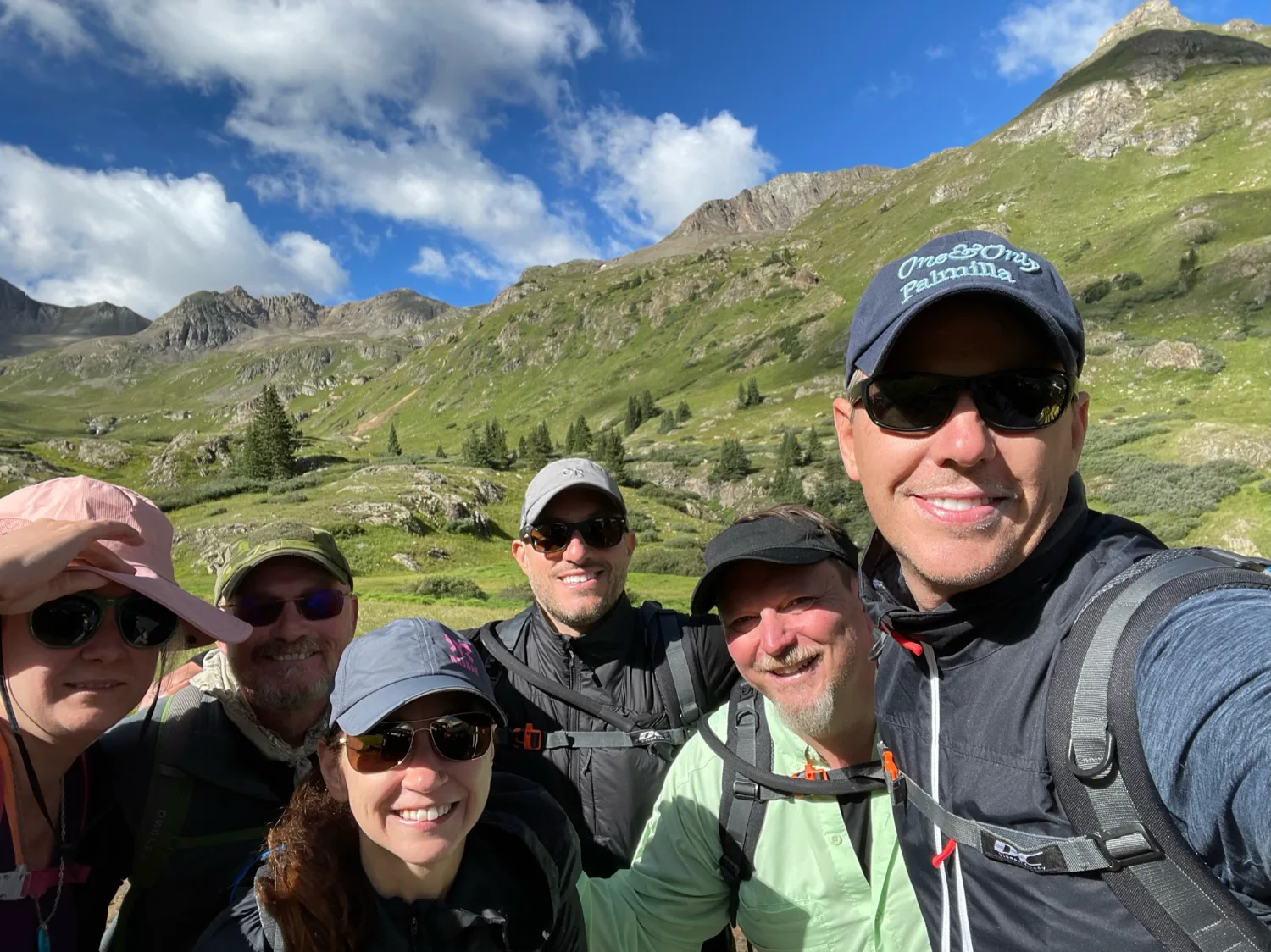 A small group of executives smiling together high in the alpine on a retreat