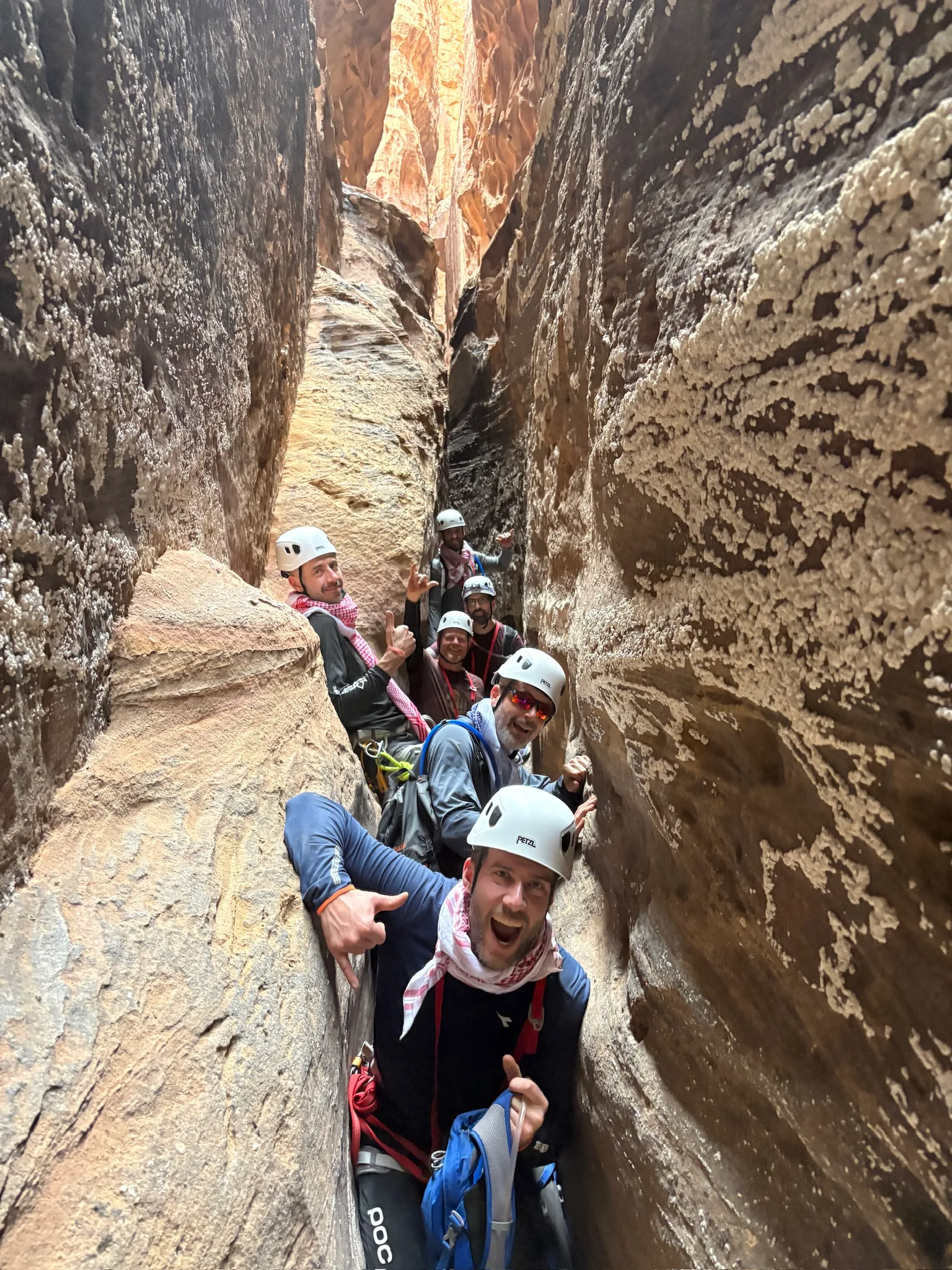 An executive team grinning together inside a slot canyon