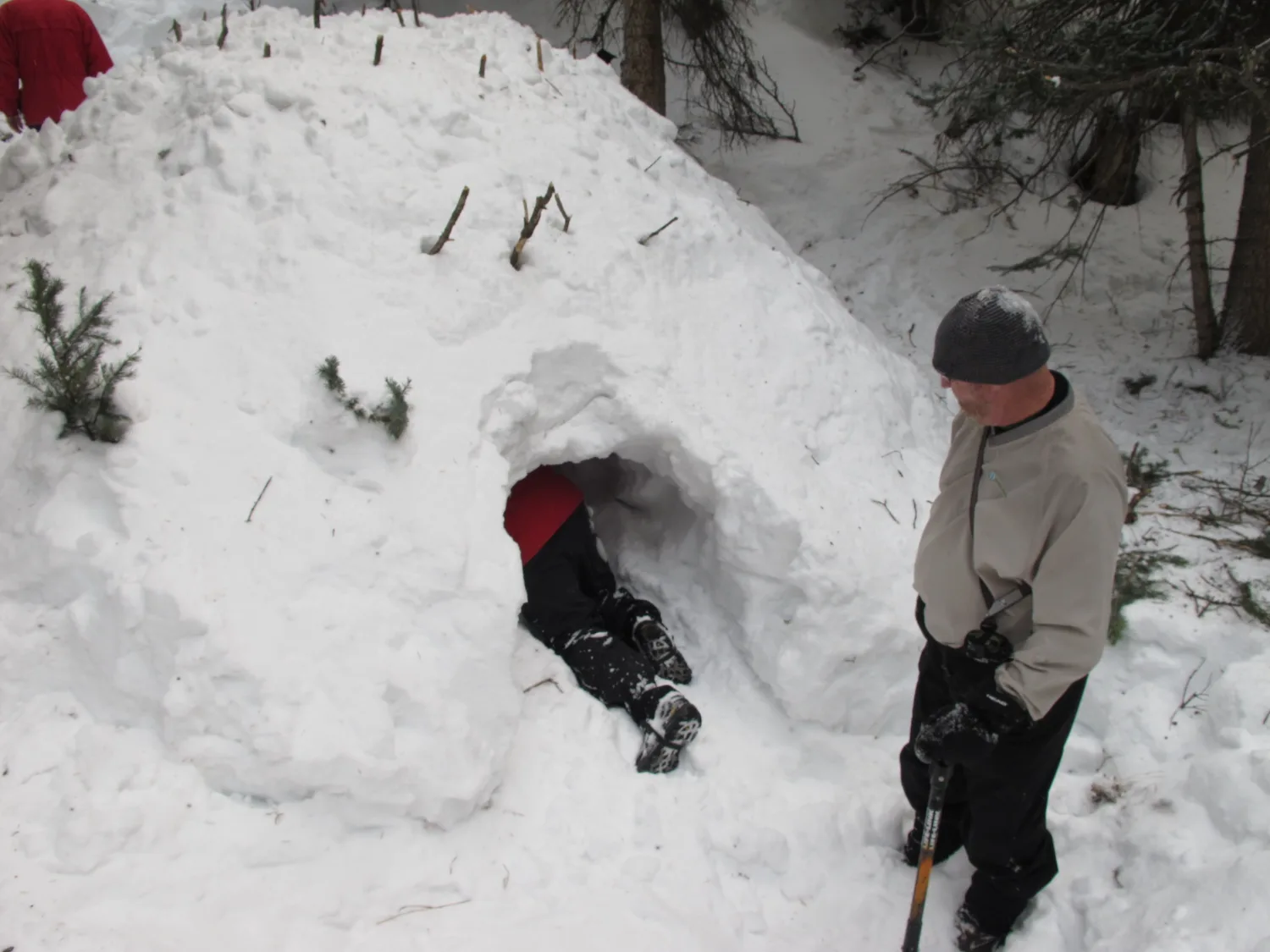 Executive crawling into a quinzhee snow shelter built by the team