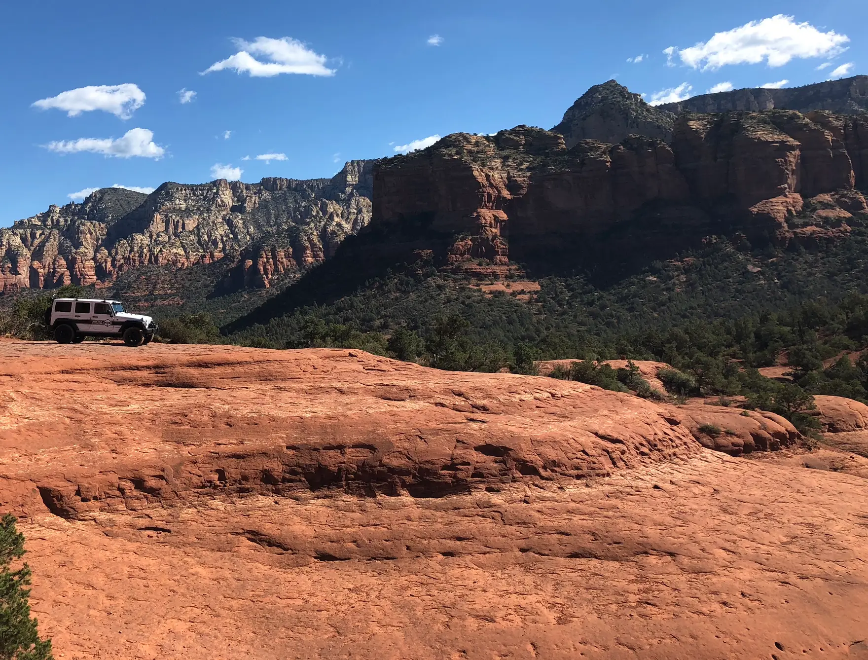 A vehicle on red slickrock below the Sedona cliffs.